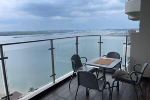 Een balkon met een tafel en stoelen, uitkijkend op een wateroppervlak.