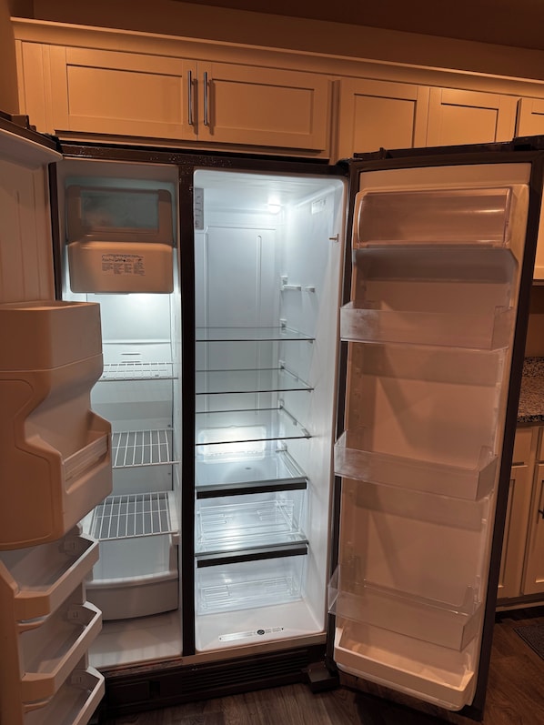 A kitchen with a white refrigerator, wooden cabinets, and a stainless steel range hood. - Cozy + Relaxing Newly built in 2025 3BR, 2BA Near Everything! (Wilson)