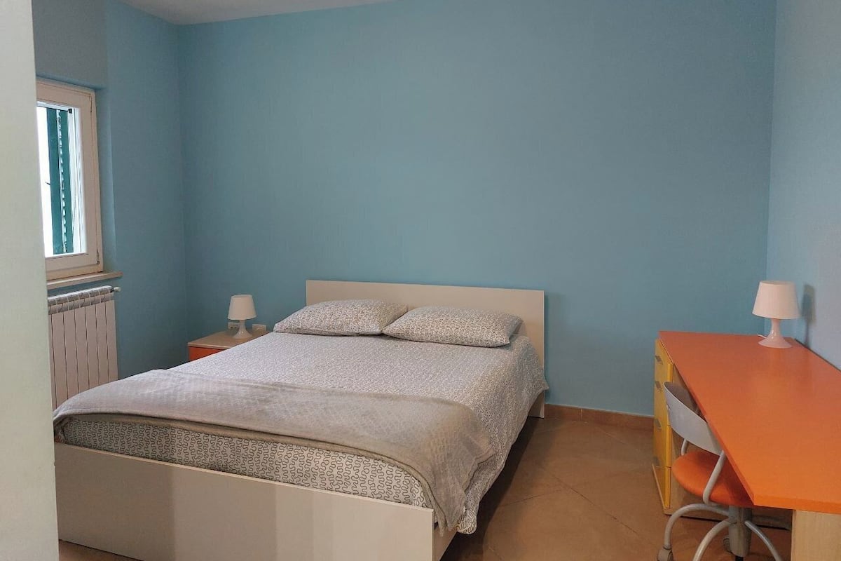 Une chambre à coucher avec un lit, deux tables de chevet, un bureau et une chaise.