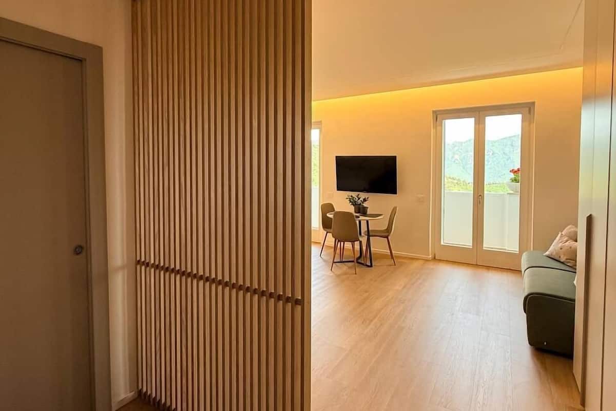 Un salon moderne avec une cloison en bois, un téléviseur à écran plat, un coin repas avec des chaises et un canapé.
