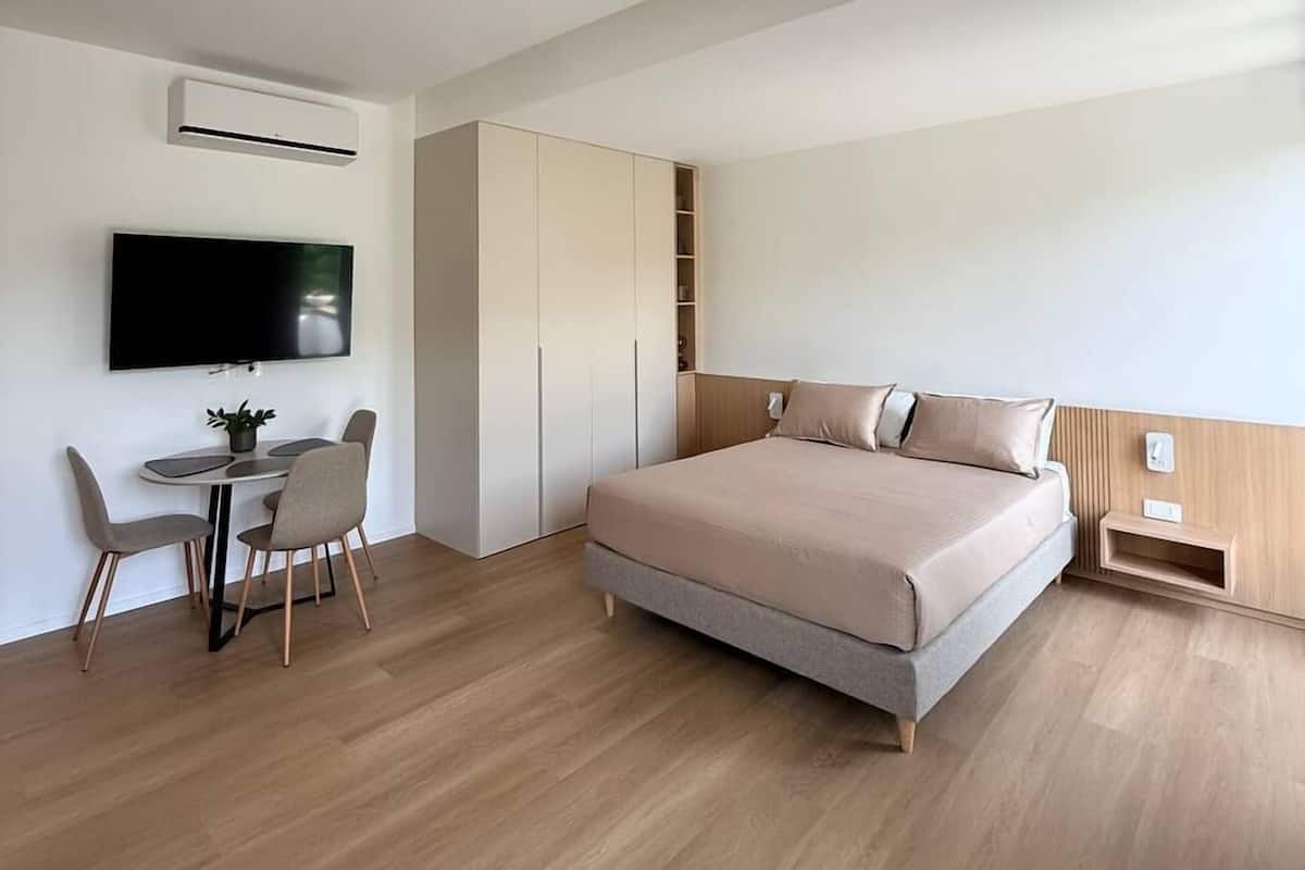 Une chambre à coucher moderne, équipée d’un lit, d’une télévision, d’un bureau avec des chaises et d’armoires intégrées.