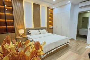Une chambre à coucher comprenant un lit, une table de chevet, une lampe, une armoire et une plante décorative.