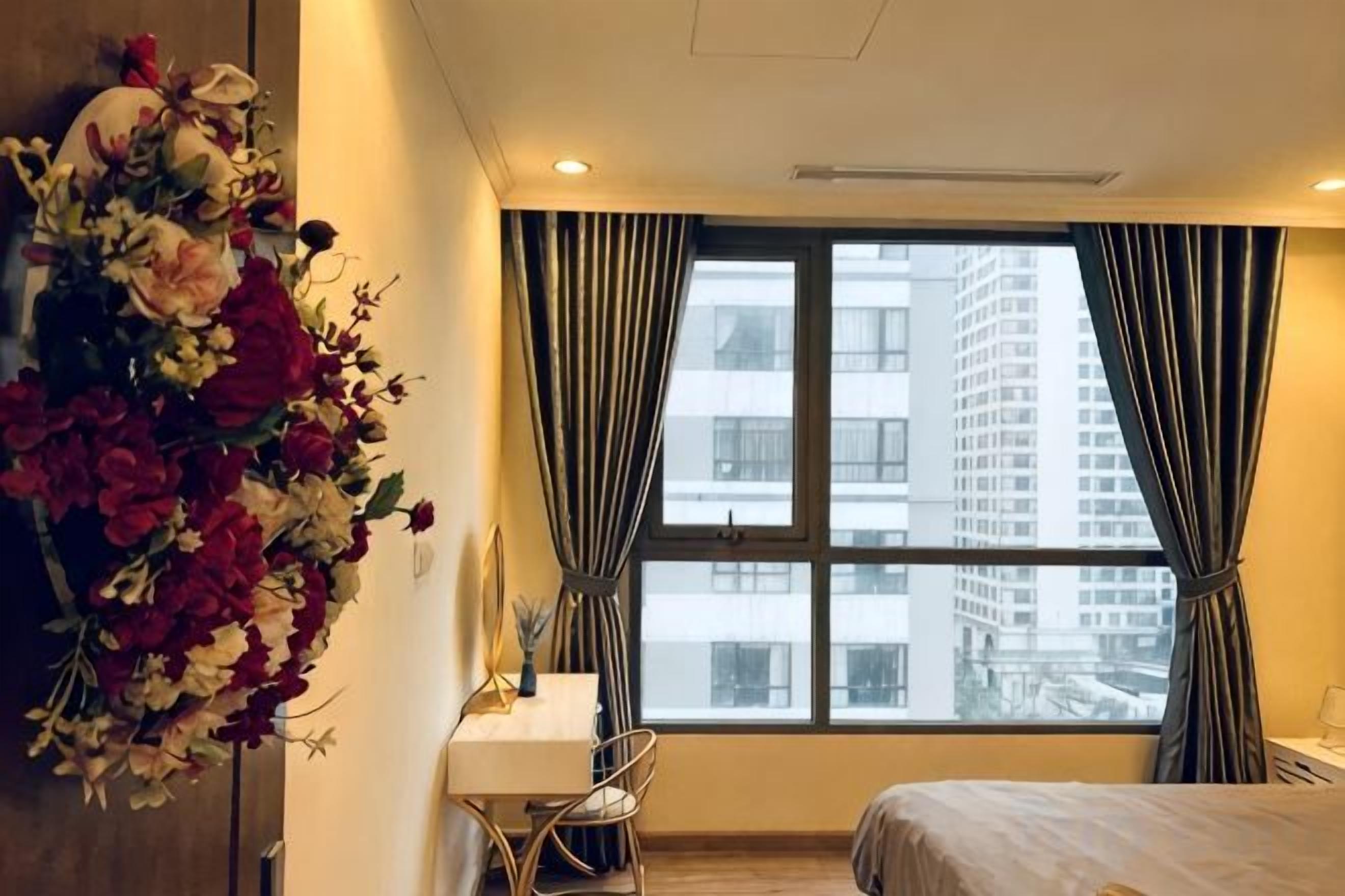 A hotel room with a bed, a desk, and a large window with curtains.