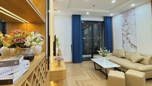 A modern living room with a sofa, coffee table, and decorative vases. - Vinhomes Time city & Park Hill - Green Home (Hanoi)