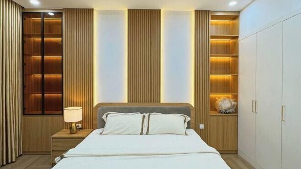 A modern bedroom with a bed, nightstands, and built-in shelving. - Vinhomes Time city & Park Hill - Green Home (Hanoi)