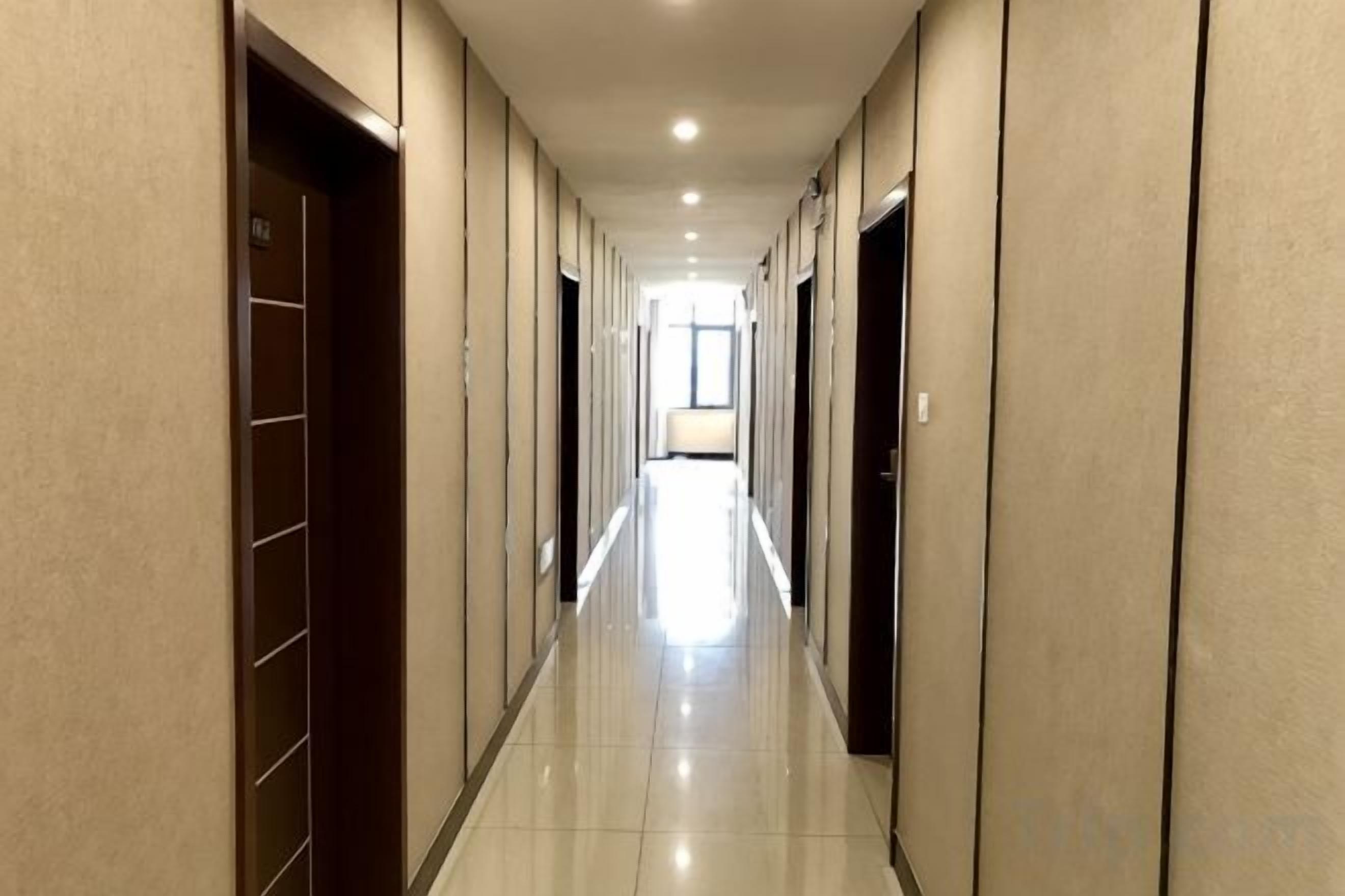 A hotel corridor with doors on both sides, a tiled floor, and a light source at the end.