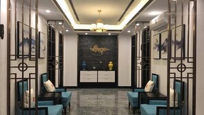 A modern hallway with blue sofas, a decorative wall, and a chandelier. - Hotel l'Orchidee Owendo (Libreville)