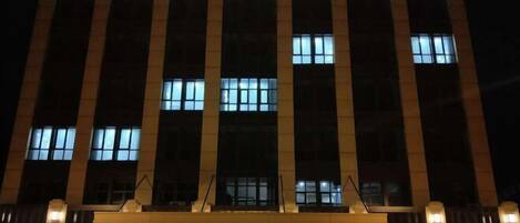 Un hotel llamado HOTEL L'ORCHIDEE con fachada moderna y señalización iluminada.