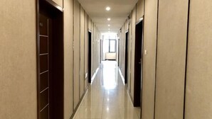 A hotel hallway with doors on both sides, a tiled floor, and a bright light at the end. - Hotel l'Orchidee Owendo (Libreville)