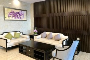 Un salon moderne avec deux canapés blancs, une table basse foncée et une œuvre d’art accrochée au mur.