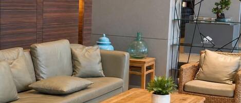 A modern living room with a sofa, a coffee table with a plant, and a wicker chair.