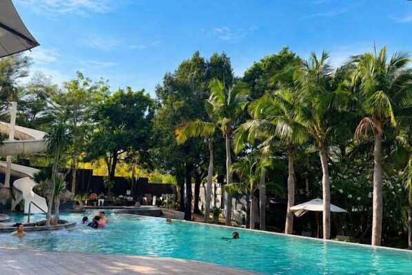 A swimming pool surrounded by palm trees and a modern building structure. - Unixx South Pattaya (Pattaya)
