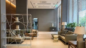 Un hall d’entrée moderne avec une cloison en verre, des canapés, une table basse et une lampe.