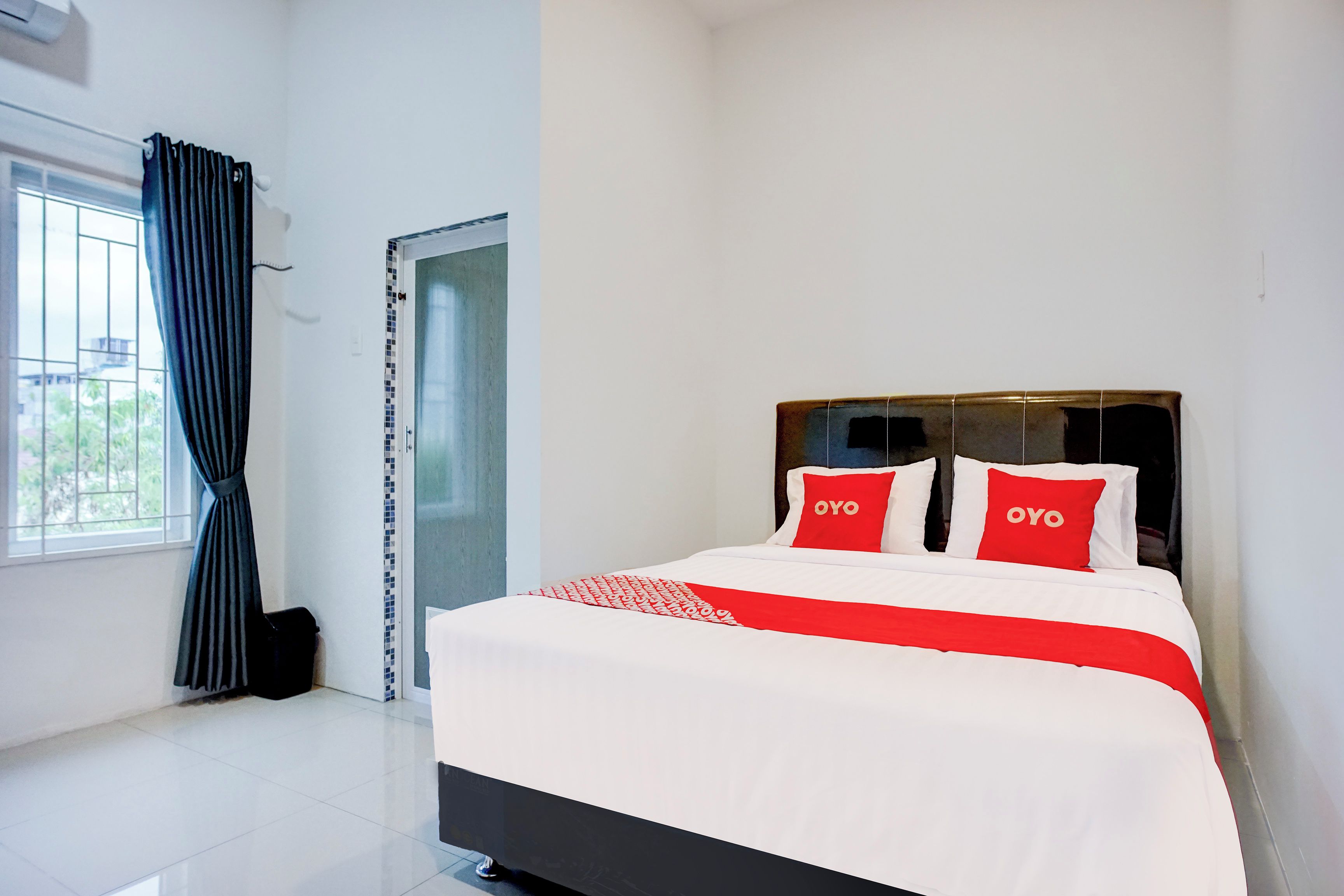 Une chambre d’hôtel avec un lit, une fenêtre avec des rideaux et une porte.