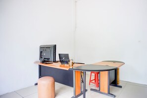 Une pièce comprenant un bureau, un ordinateur, une imprimante et un tabouret rouge.