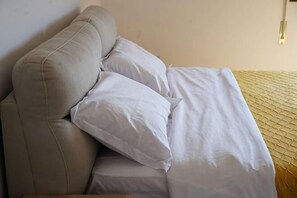 Ein Bett mit weißer Bettwäsche und einem Kopfteil.