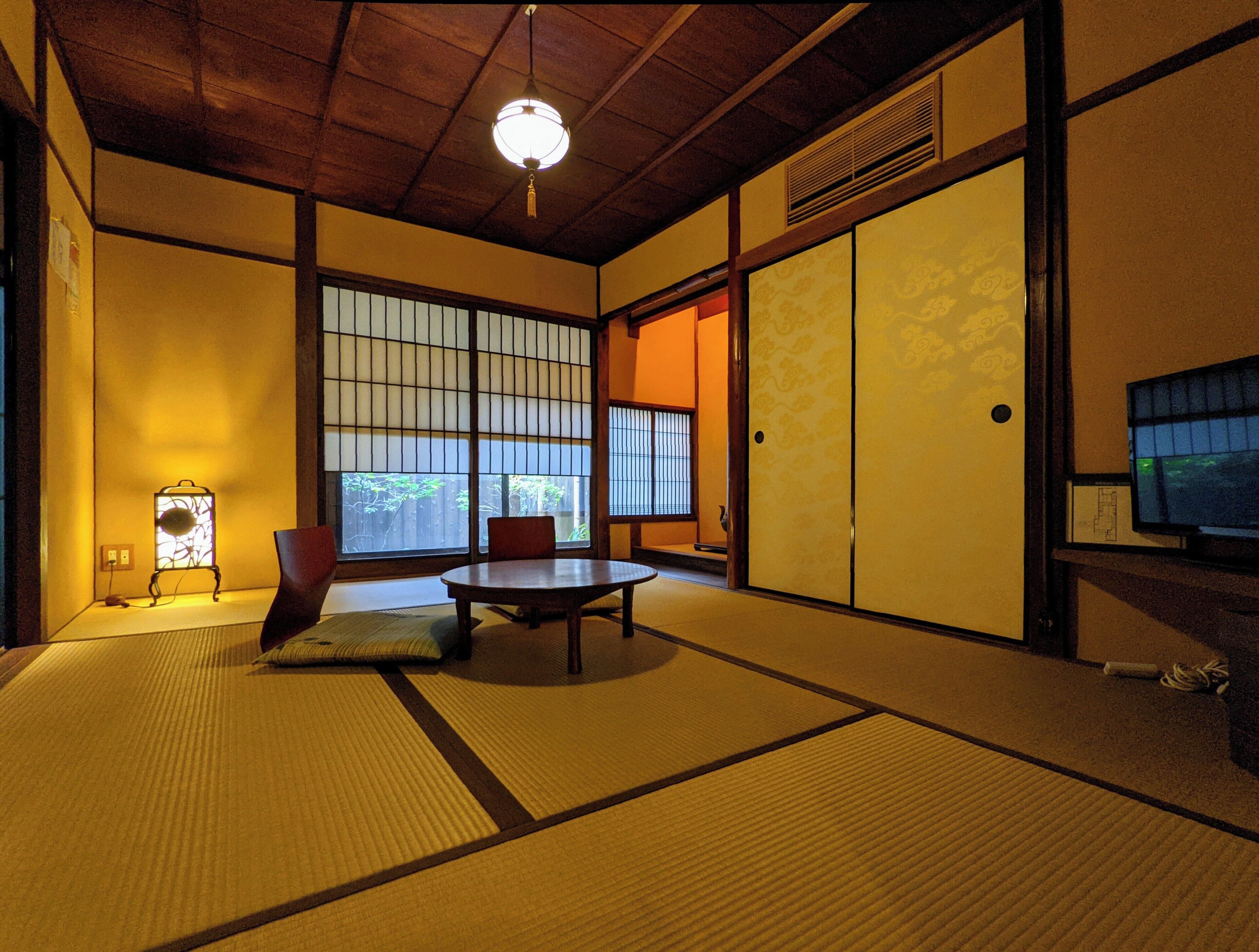A traditional Japanese room with tatami flooring, a low table, and sliding doors.