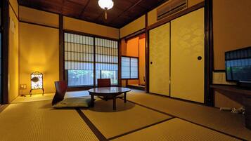 A traditional Japanese room with tatami flooring, a low table, and sliding doors.