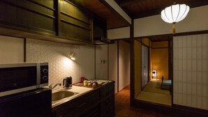 A compact kitchen with a microwave, sink, and cabinets. There is a traditional Japanese lantern hanging above the counter. - Kyomachiya Hoshiya (Kyoto)
