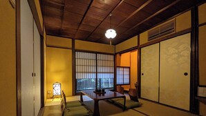A traditional Japanese room with tatami flooring, a low table, sliding doors, and a view through a shoji screen. - Kyomachiya Hoshiya (Kyoto)