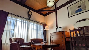 A room with a wooden table, two chairs, a lamp, a clock, a dresser, and a framed picture on the wall. - Kyomachiya Hoshiya (Kyoto)