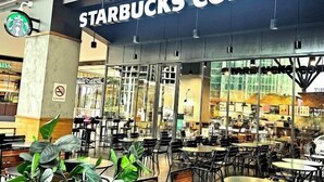 Ein Starbucks Kaffeehaus mit modernem Interieur, das mehrere Sitzbereiche und große Fenster bietet.