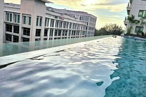 A swimming pool with a glass edge, adjacent to a building with multiple windows and a flat roof. - The Loft Imago KK Time Square - 4 Bedrooms/ 10 PAX (Kota Kinabalu)