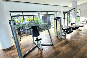 A gym with exercise equipment, large windows, and a view of greenery. - The Loft Imago KK Time Square - 4 Bedrooms/ 10 PAX (Kota Kinabalu)