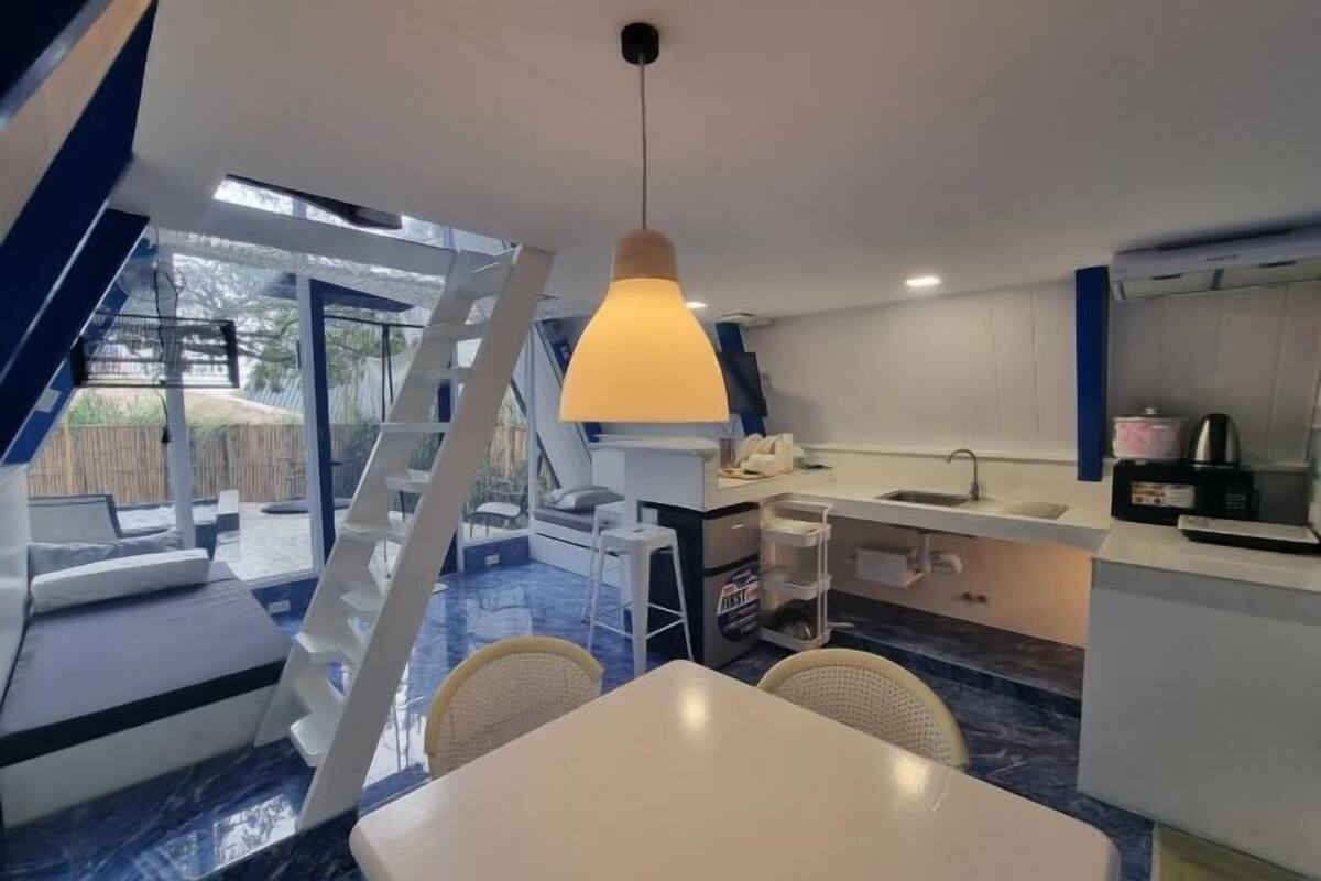 A modern kitchen with a dining area, a staircase, and a view of the outdoors.