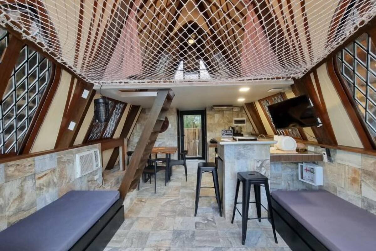 A cozy, enclosed space with a stone floor, wooden beams, and a netted ceiling.