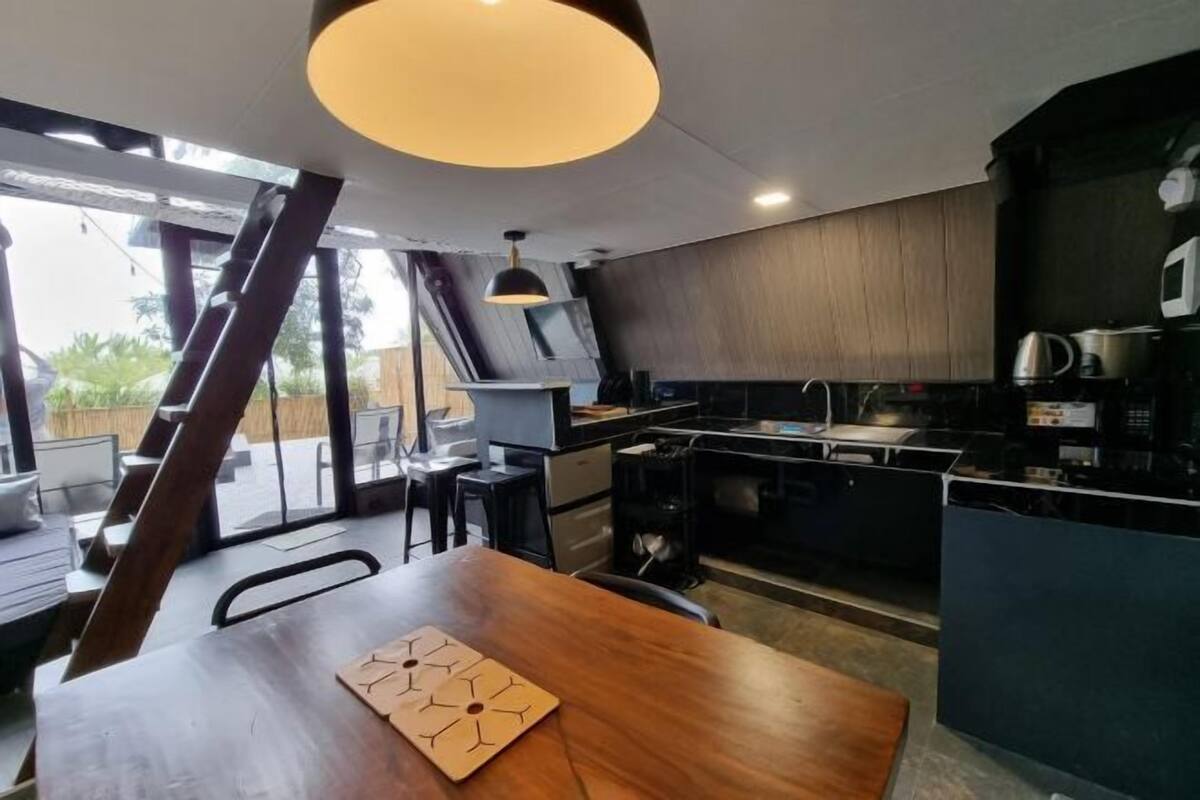 A modern kitchen with a dining area, large windows, and a unique ceiling design.