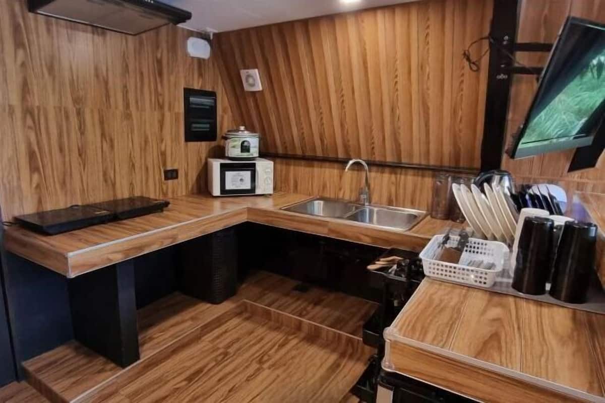 A compact kitchen with wooden walls, a built-in sink, and a small countertop.