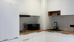 Cuina moderna amb armaris blancs, un microones negre i un taulell de fusta.