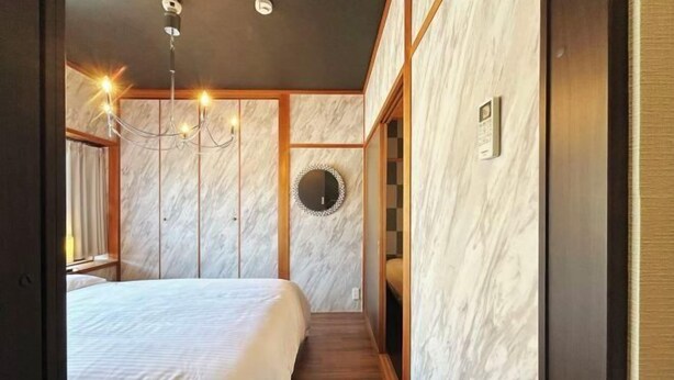 A bedroom with a large bed, a chandelier, a mirror, and wooden paneling.