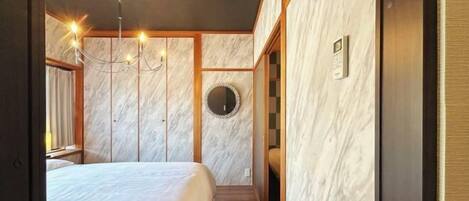Un dormitorio con una cama grande, una araña, un espejo y paneles de madera.