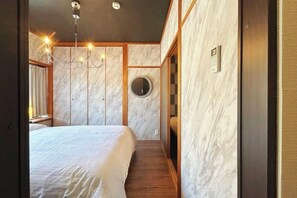 A bedroom with a large bed, a chandelier, a mirror, and wooden paneling. - Rakuyado kyotofushimi II (Kyoto)