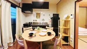 A compact hotel room with a dining area, kitchenette, and a bed.