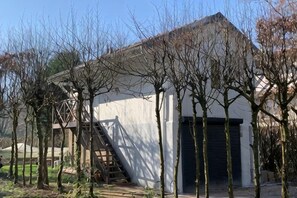 Un edificio con una escalera que lleva a una puerta, rodeado de árboles desnudos.
