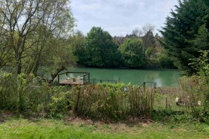 A lakeside view with a dock and a small wooden structure. - Romantic Nature Chalet – Peaceful Escape by the Marne River (Isles-les-Villenoy)
