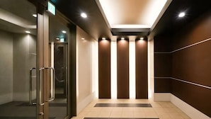 A corridor with glass doors, a tiled floor, and a wall with vertical lines. - He Yue Umeda West 401 Direct trains to Umeda (Osaka)