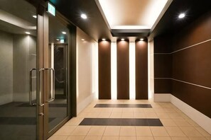 Un pasillo con puertas de vidrio, suelo de baldosas y pared con líneas verticales.