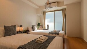 A bedroom with two beds, a ceiling light, a window with curtains, and a plant. - He Yue Umeda West 401 Direct trains to Umeda (Osaka)