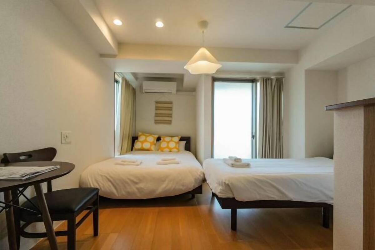 Ein Hotelzimmer mit zwei Betten, einem Schreibtisch und einem Stuhl.