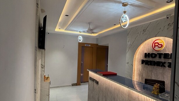 A hotel reception area with a modern design, including a reception desk, a sign for the pantry, and a reception area. - Hotel Prenix Sky- Gota (Ahmedabad)