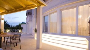 An outdoor patio with a table and chairs, large windows, and a wooden pergola. - Luxury Apartment Split with pool (Split)