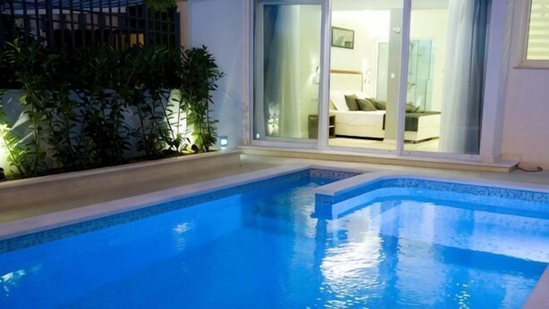 A swimming pool with a view of a room through a glass door. - Luxury Apartment Split with pool (Split)