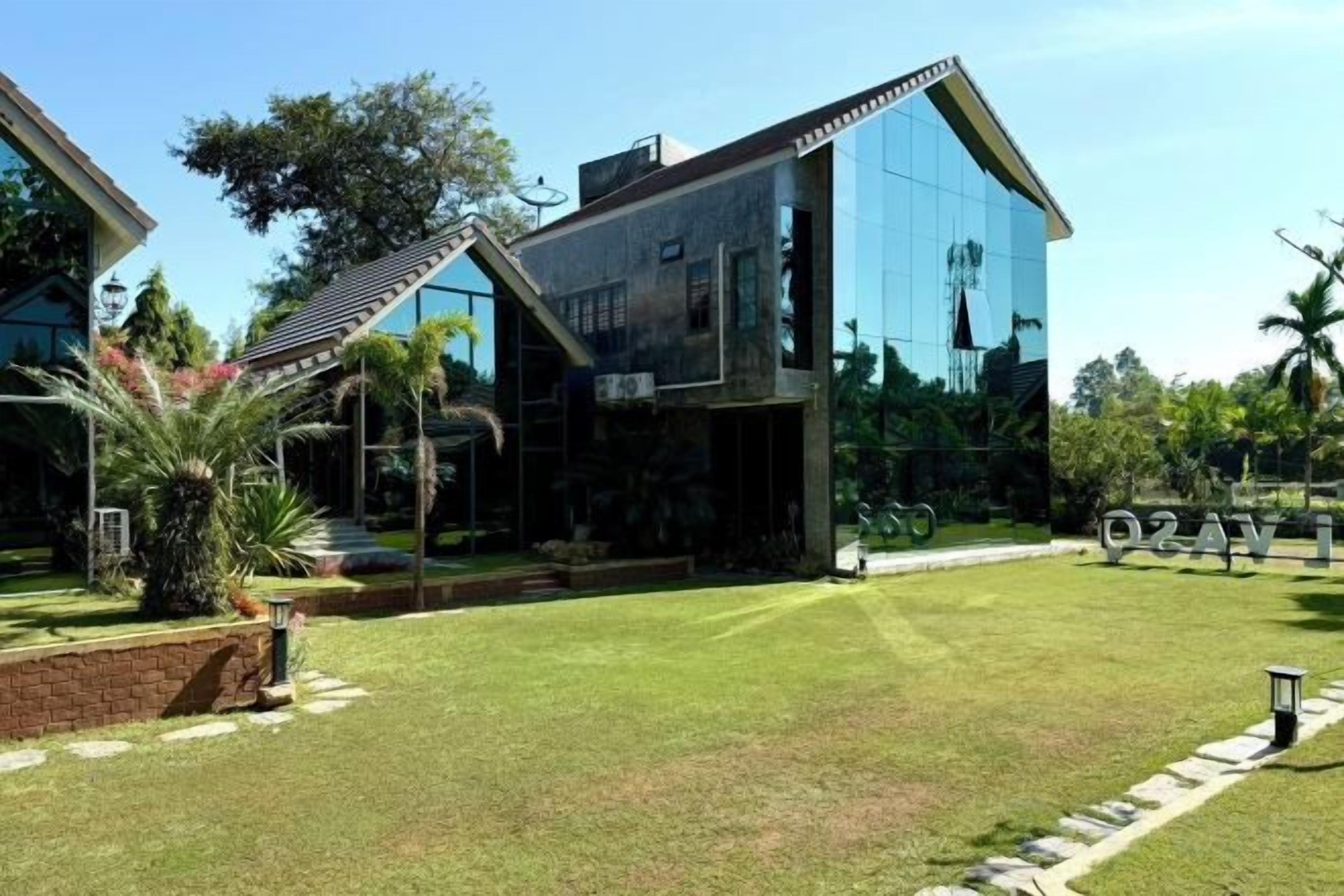 A modern house with a large glass facade, a well-maintained lawn, and a clear sky.