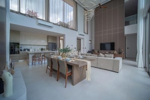 A spacious living area with a dining table, sofa, and TV.