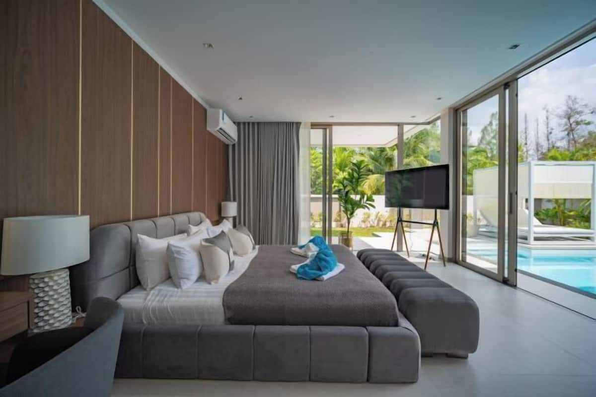 Une chambre moderne avec un grand lit, une télévision et une vue sur une piscine.