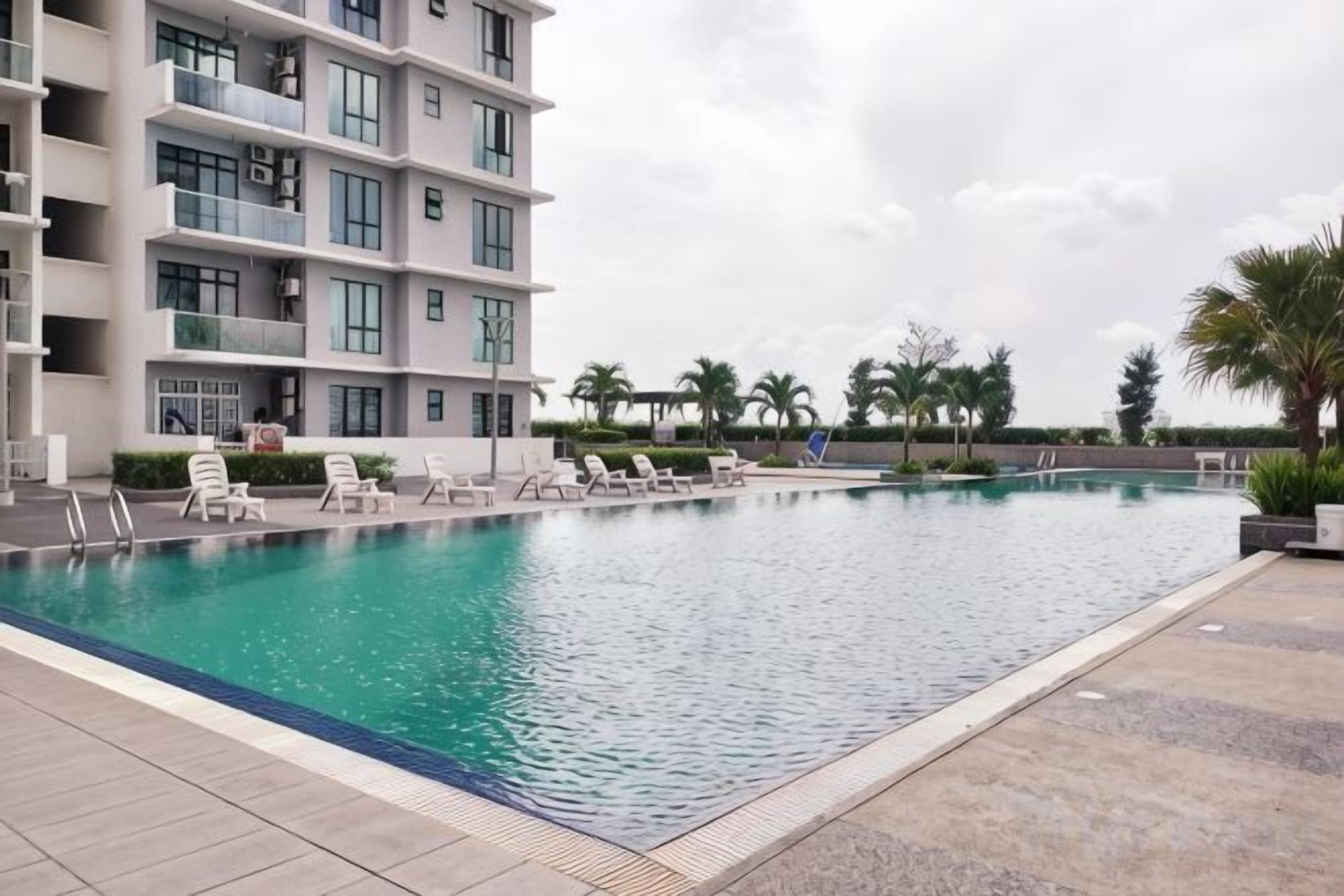 A swimming pool with lounge chairs and a building with balconies.